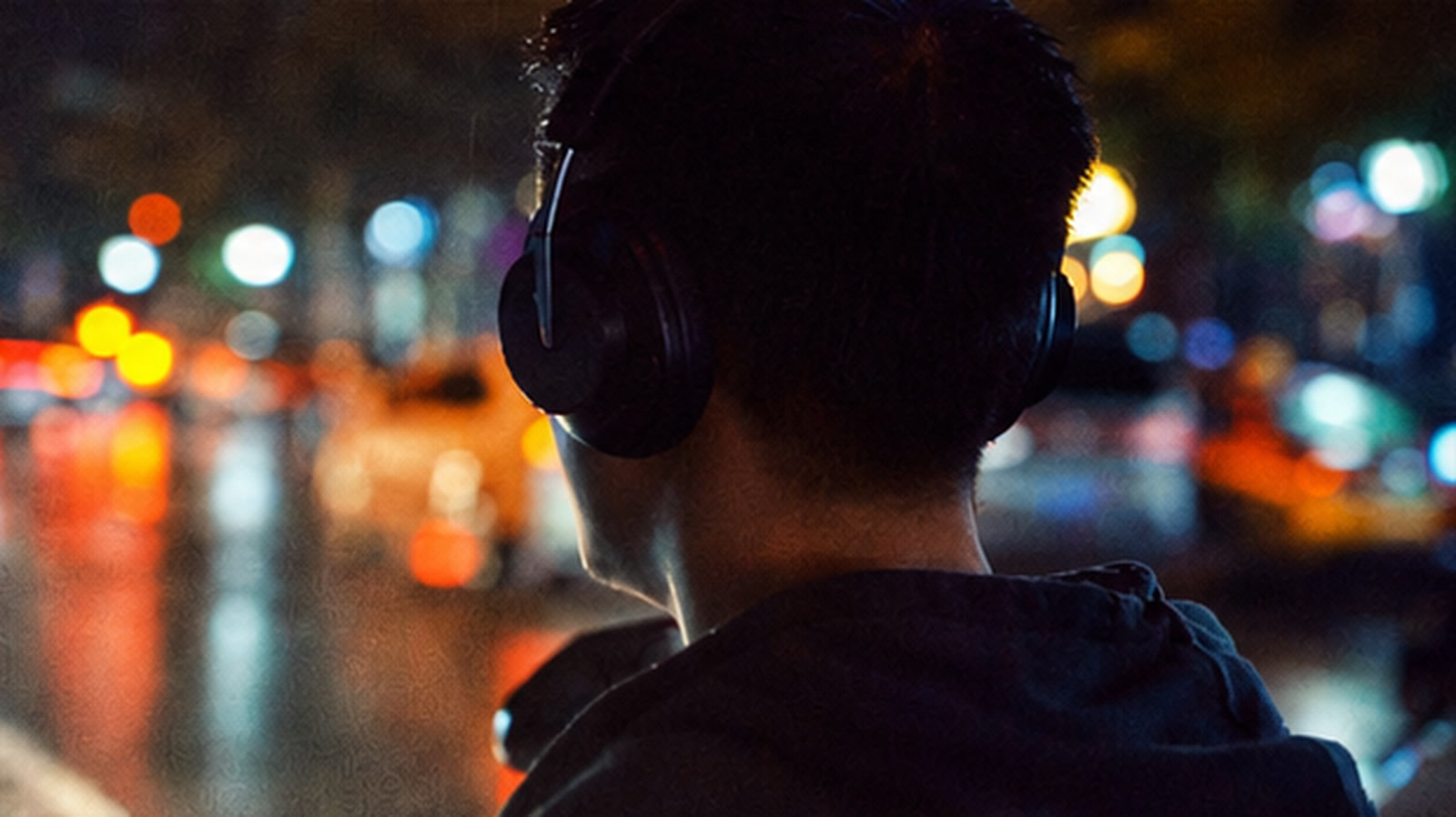 A man wearing headphones in the city at night