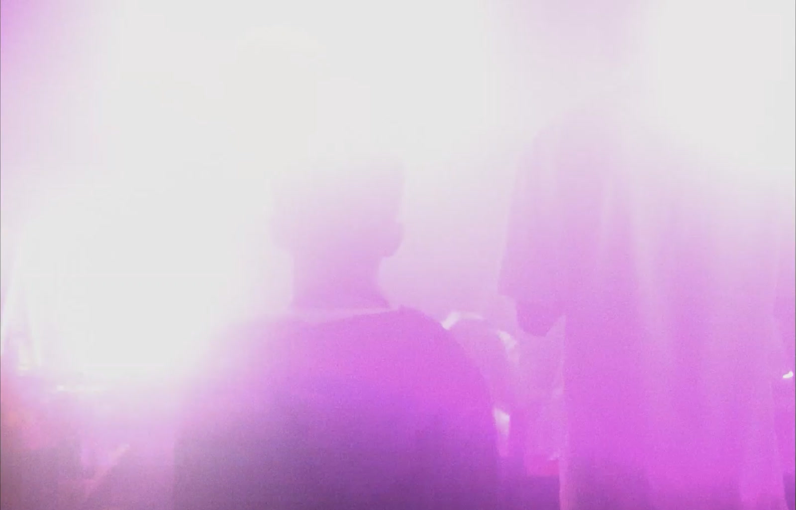A figure in soft pink and purple club light