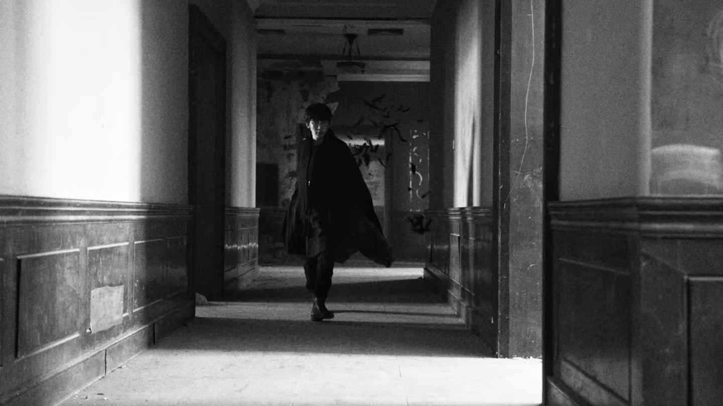 A figure walking through a sunlit corridor
