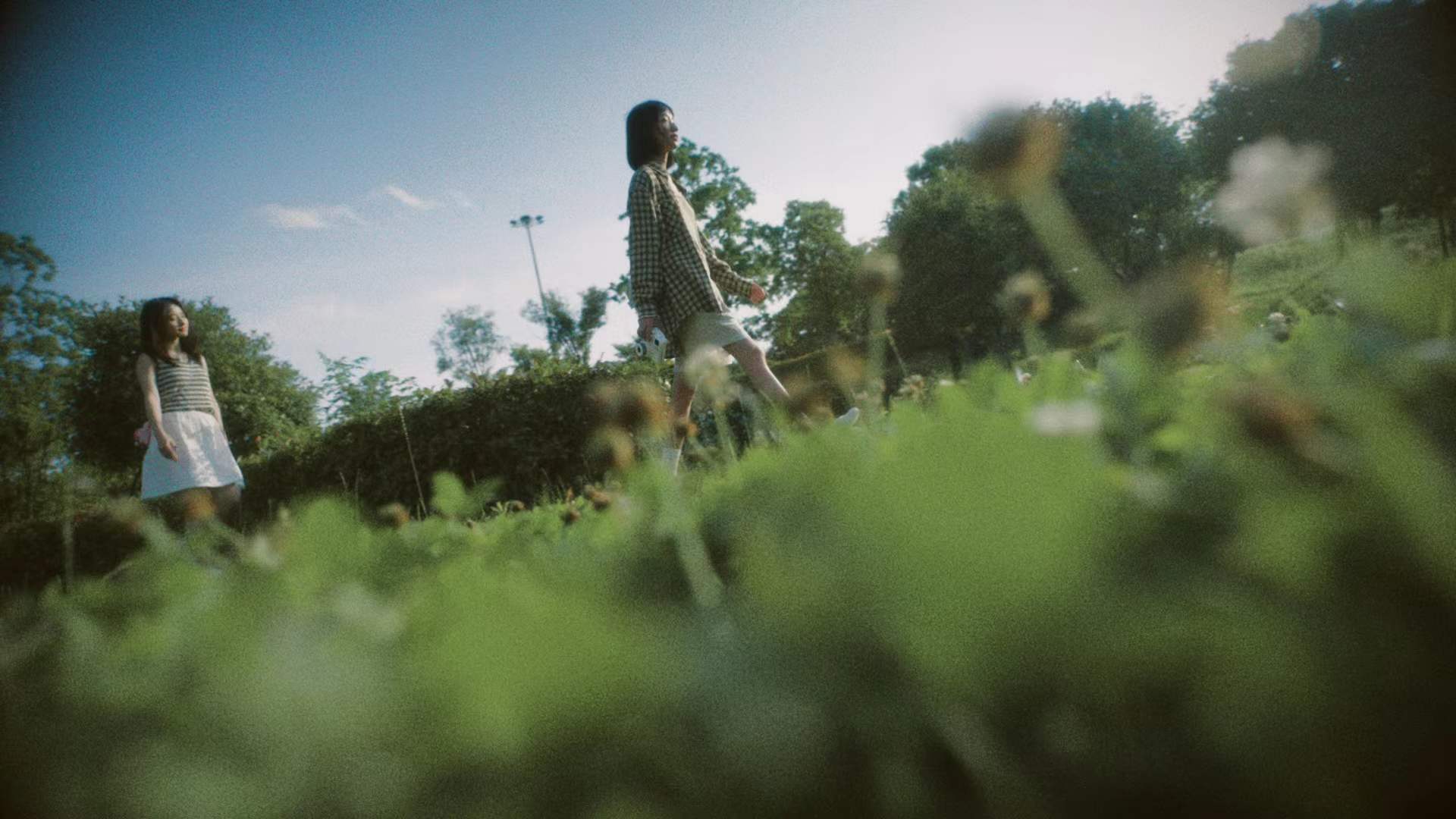 Two women walking through a sunlit garden