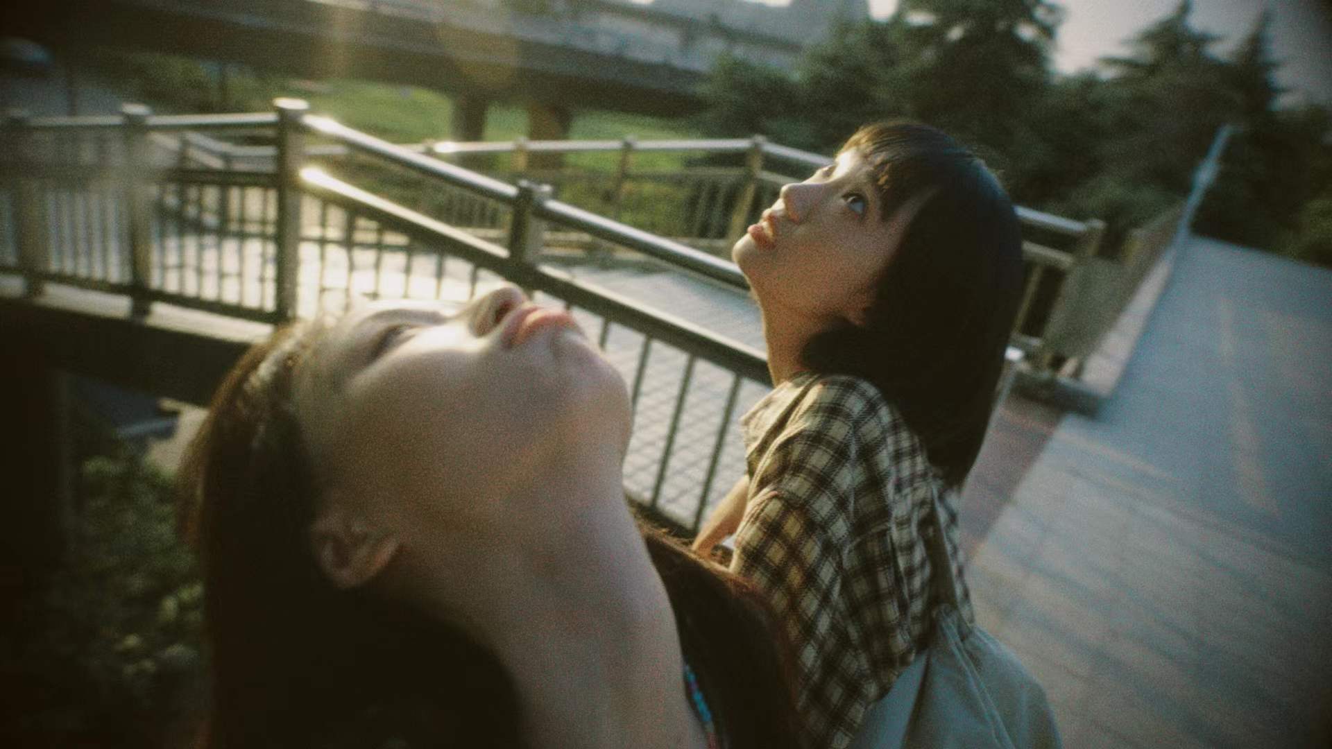 Two women looking upward beside a railing
