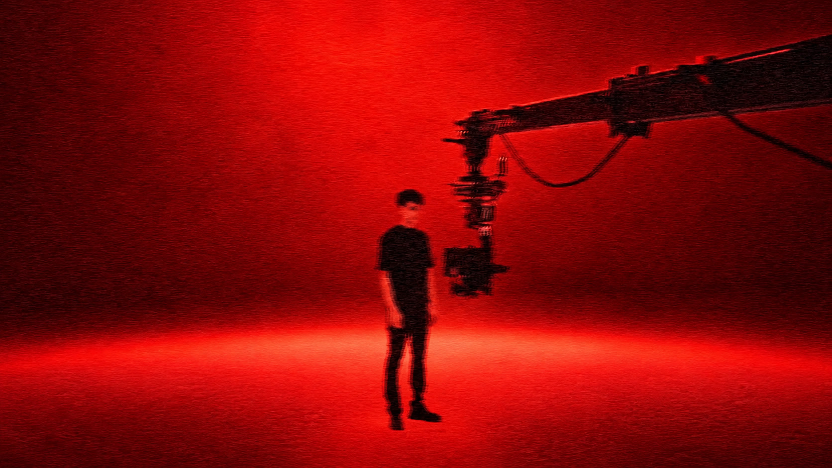 HENNESSY — a figure and camera crane against warm light