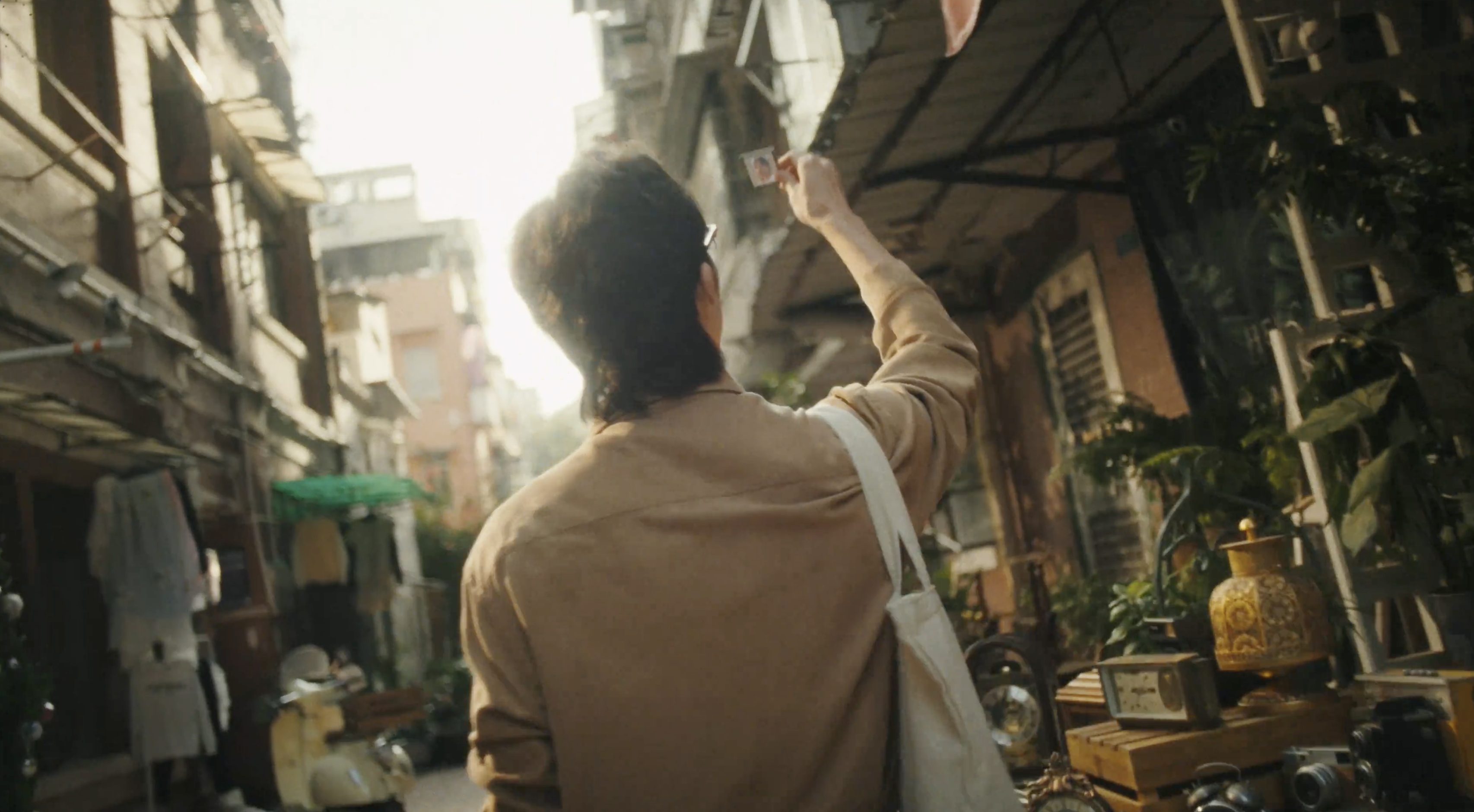 A figure holding a photograph in a sunlit alley