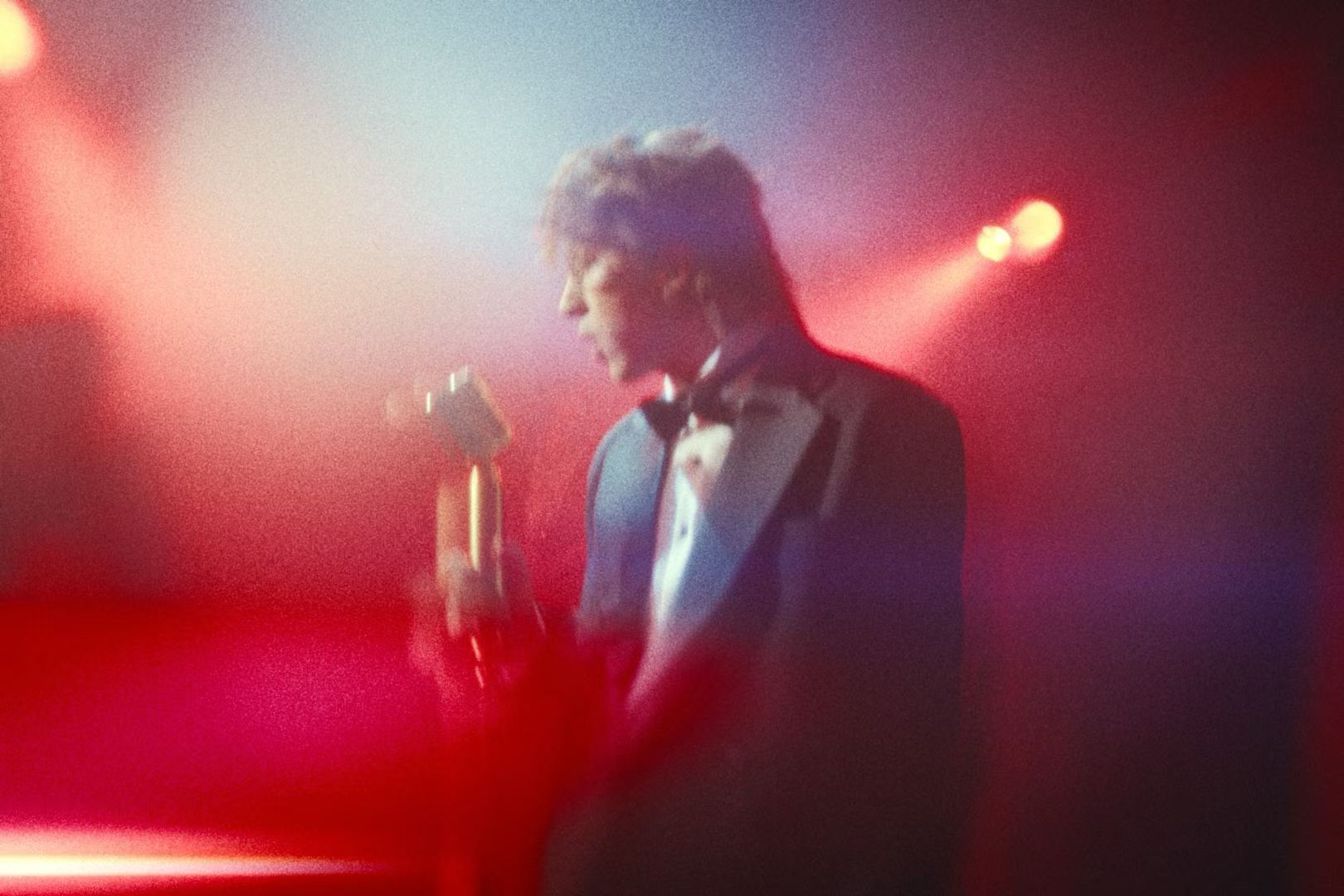 A singer holding a microphone in red light