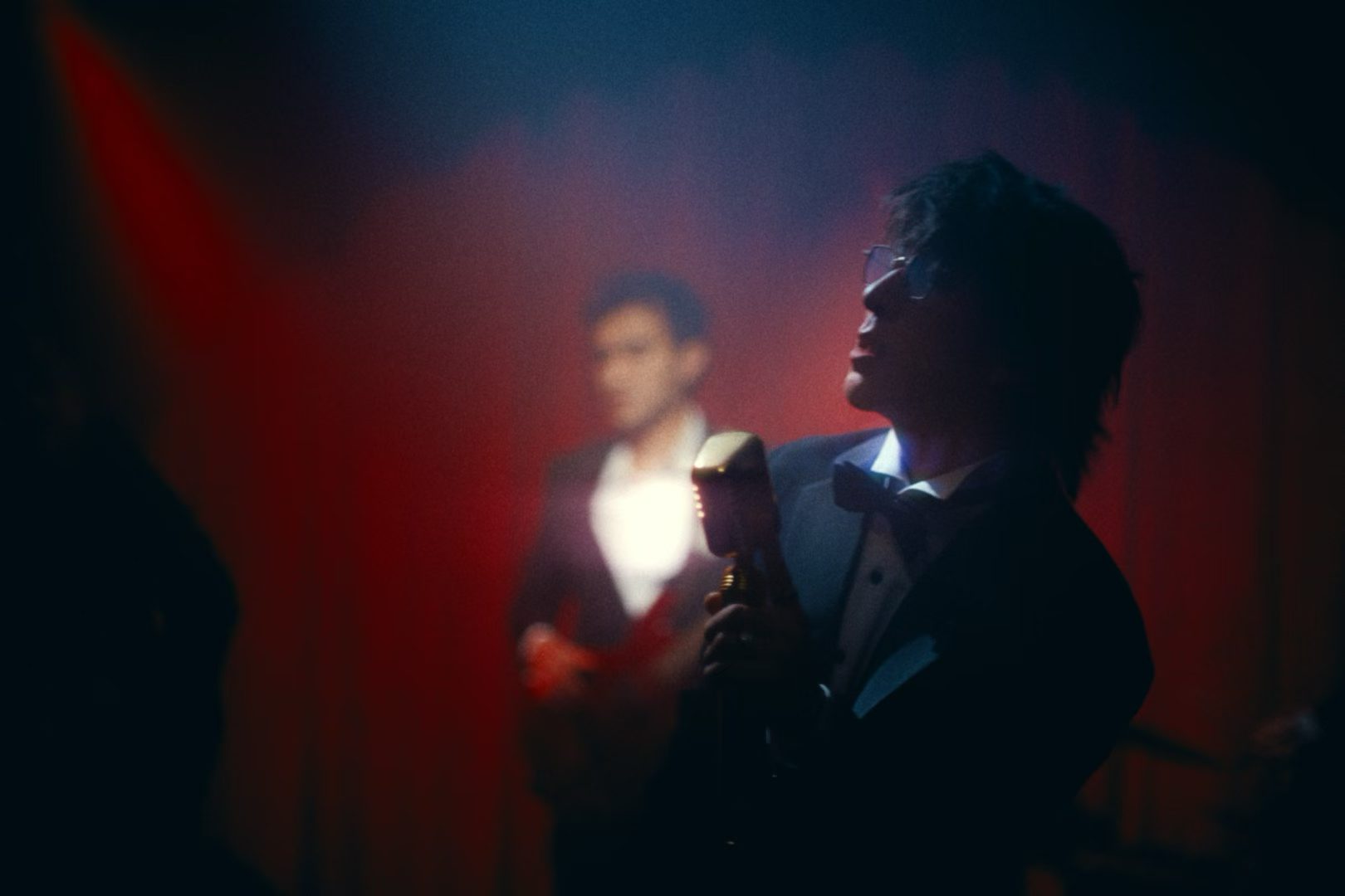 A singer and musician on a red-lit stage