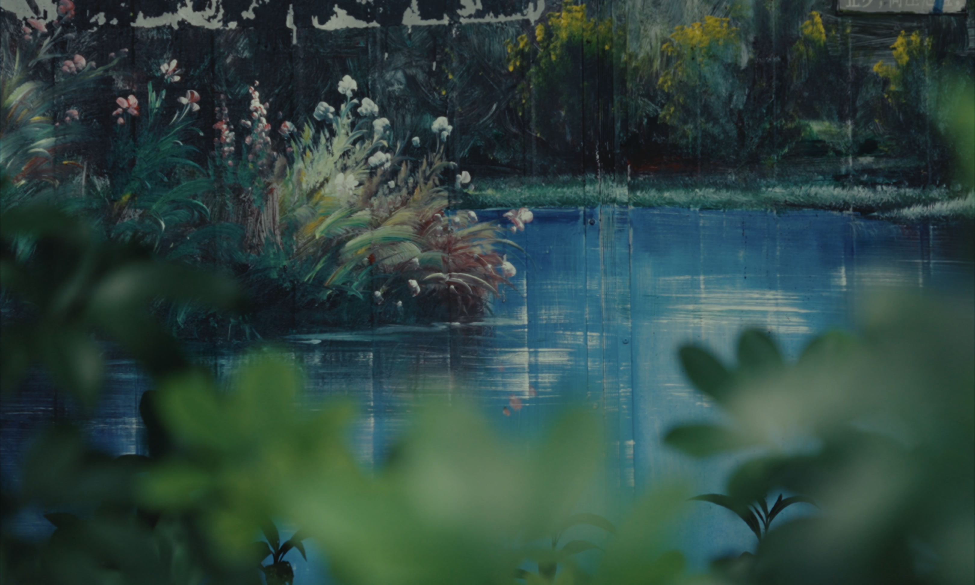 A painted pond and flowers seen through leaves