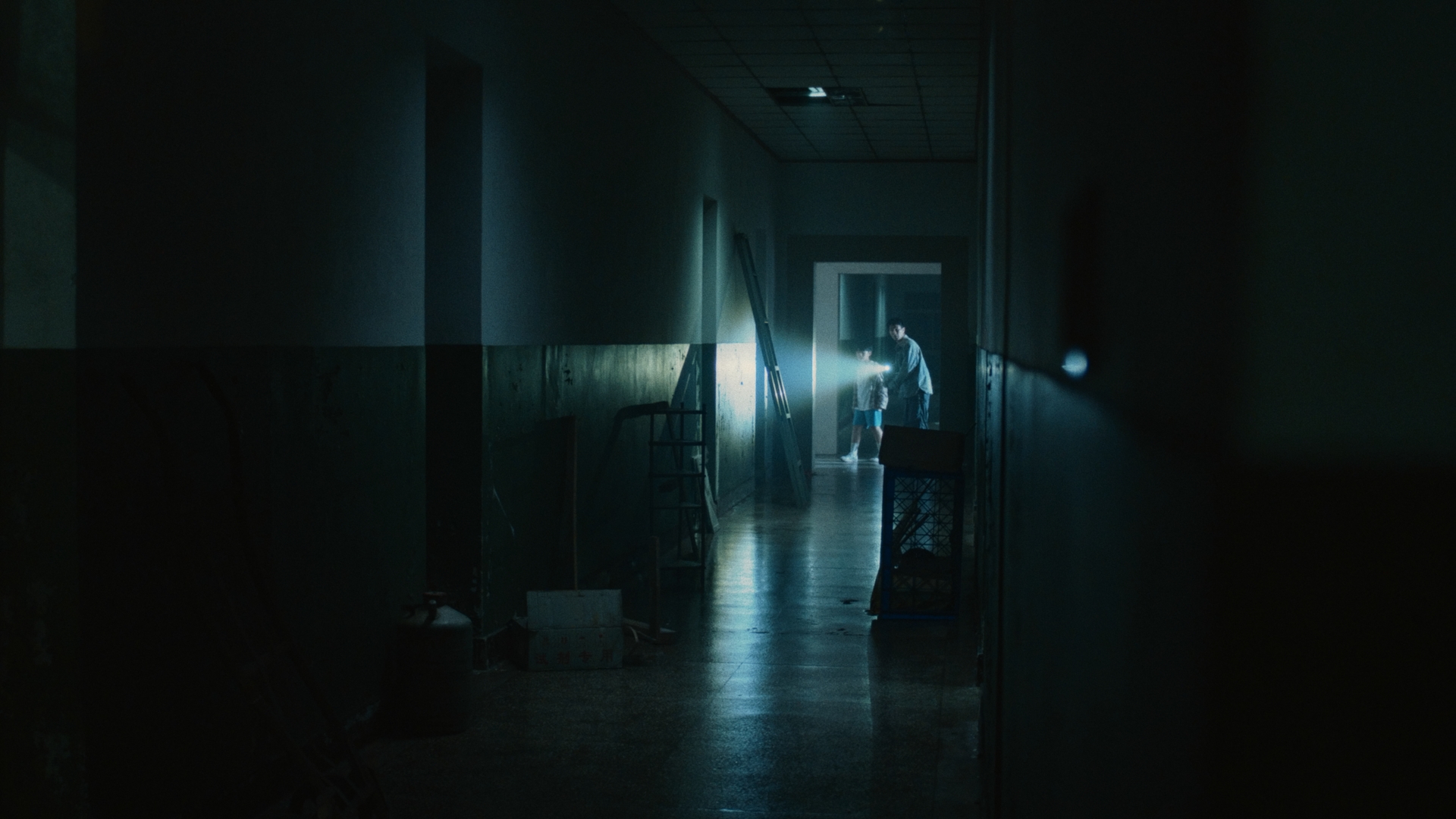 Two figures in a dark corridor