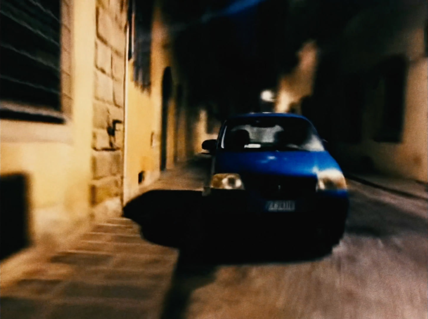 A blue car on a narrow street