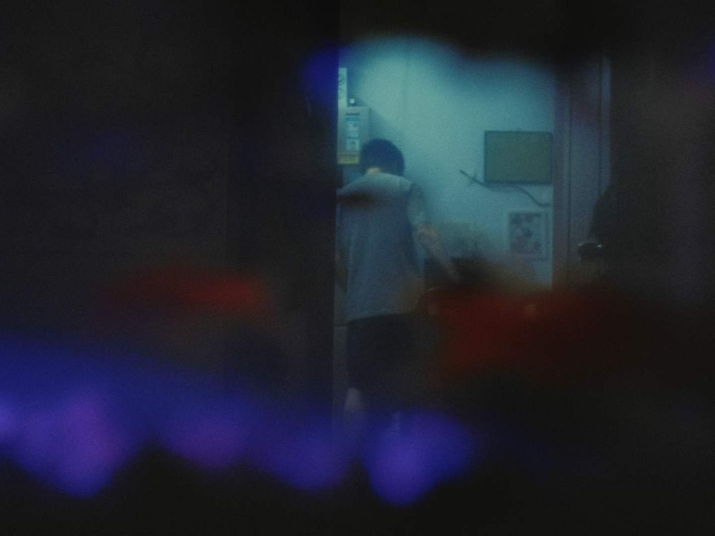 A figure seen through a blue-lit doorway