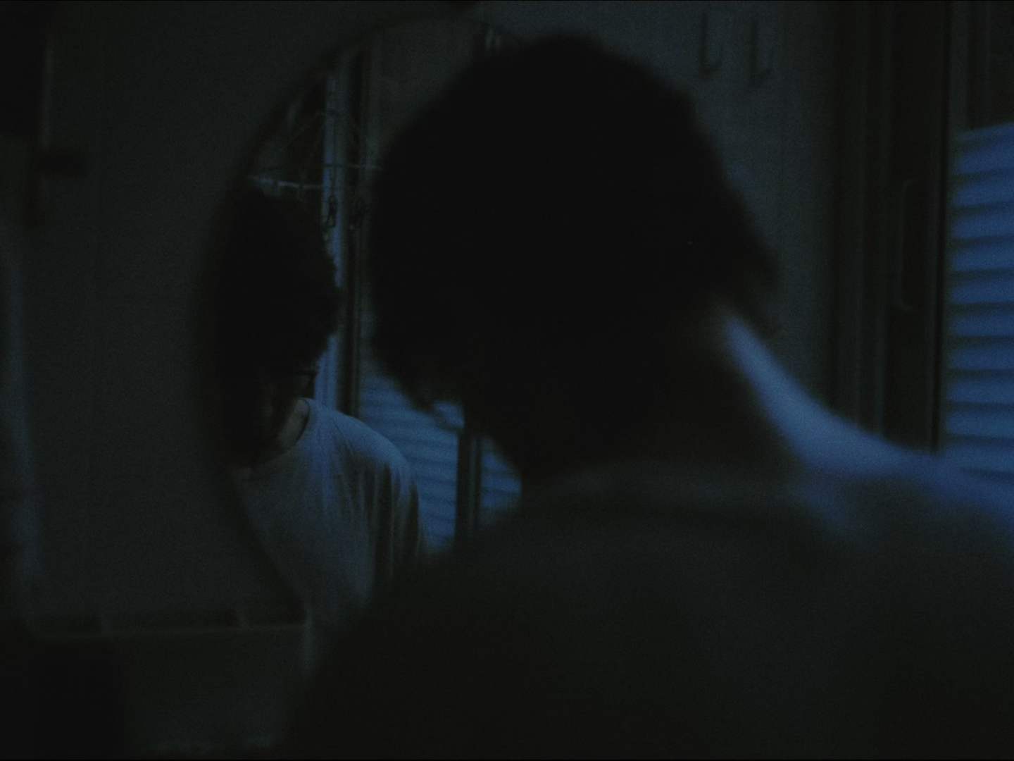 REARVIEW MIRROR — a figure reflected in a dim blue mirror