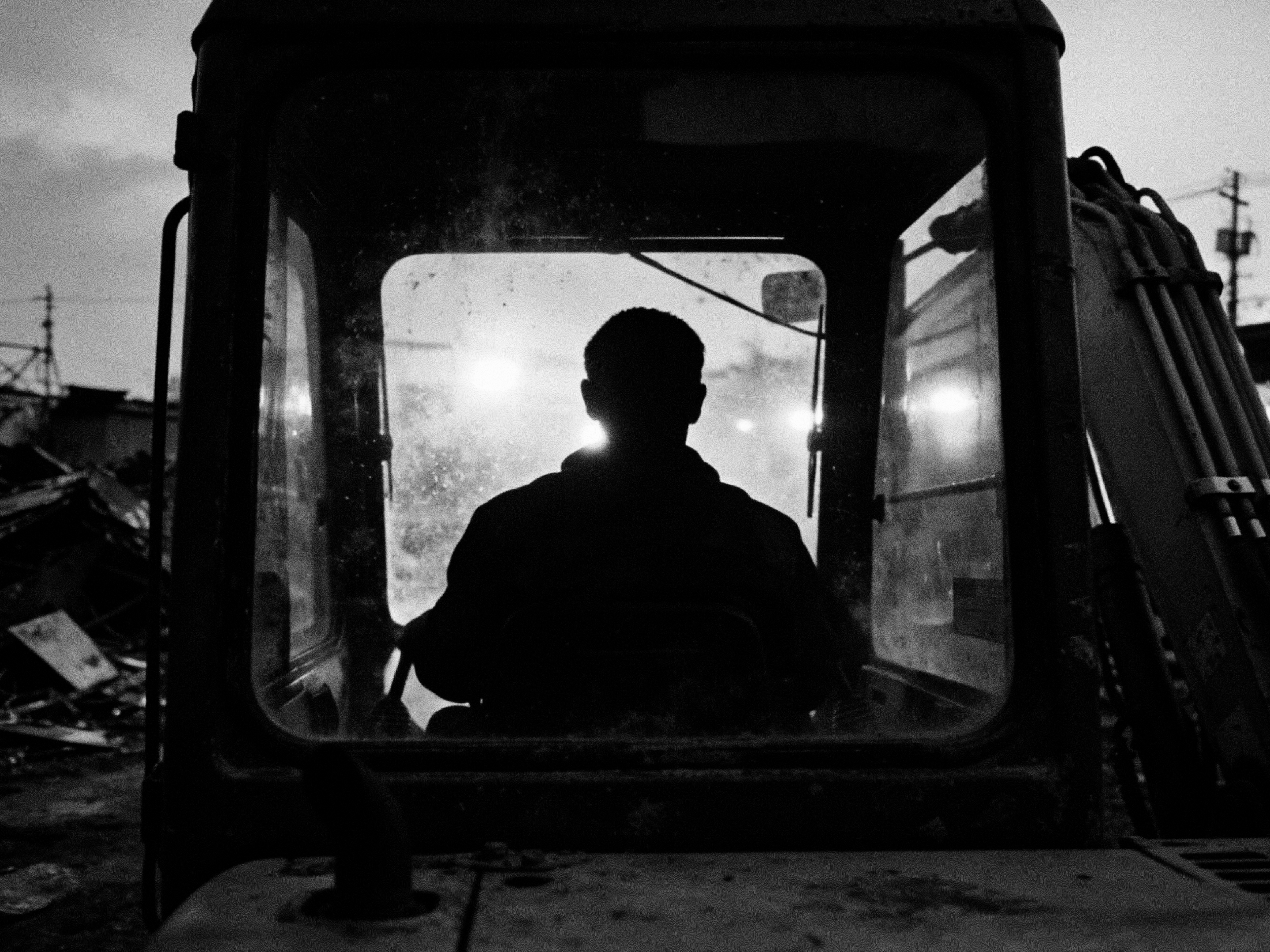 SYNC — an excavator operator silhouetted in the cab